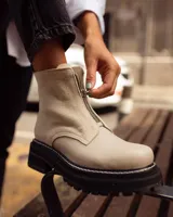 Botas cortas color beige con cierre frontal de cremallera, suela track negra y tirador trasero.