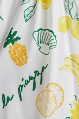 Vestido corto blanco con estampado de bananas, limones, piñas y sombrillas. Tiene breteles finos ajustables, escote corazón y cuerpo entallado con frunces en el escote y laterales. La falda es levemente acampanada.