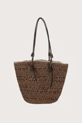 Bolsa tejida en tonos café y negro, con asas en marrón oscuro y colgante de marca en dorado.