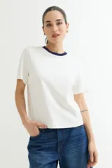 Remera blanca de algodón con cuello redondo y mangas cortas. El cuello es de color azul marino en contraste.