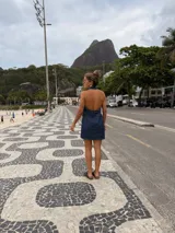 Vestido corto de jean azul, sin mangas, con cuello camisero, cierre frontal con botones y bolsillos en el pecho.