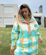 Buzo largo con cuello alto de polar color crema y cuerpo con estampado de cuadros en tonos celeste, amarillo y blanco.