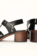 Sandalias plateadas de cuero con tiras entrecruzadas y hebilla lateral. Taco de madera de 6 cm.
