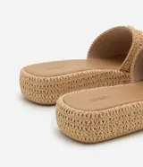 Sandalia plana flatform color beige, con textura trenzada y apliques de colgantes metálicos con motivos marinos.