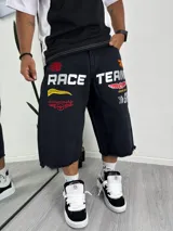 Bermuda de jean negro, corte ancho y largo (tipo culotte o capri), con terminación deshilachada en el ruedo. Presenta bordados grandes en blanco, rojo y amarillo con temática de carreras y equipos de competición.