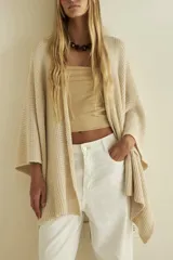 Ruana abierta de hilo de algodón color crema, con mangas 3/4 y terminación irregular.