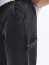 Pantalón jean celeste de corte amplio, estilo carpintero, con bolsillos laterales y traseros.