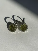 Par de aros colgantes con argolla de acero quirúrgico, dije circular de resina negra y borde de strass plateado.