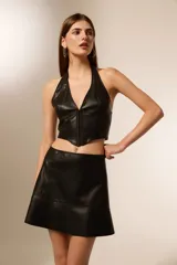 Top negro de cuero sintético con escote halter, corte al cuerpo y cierre frontal con alamares.