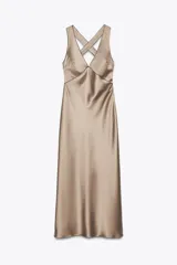 Vestido largo de satén color champagne, con escote en pico, tirantes anchos cruzados en la espalda y ribetes negros en contraste.