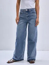 Pantalón de jean color beige, de corte wide leg, con bolsillos delanteros y traseros, y ruedo desflecado.