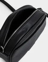 Bandolera negra de cuerina con bolsillo frontal con tag de metal, correa regulable, cierre superior y tirador de material principal.