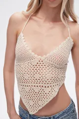 Top tejido al crochet color crema, con cuello halter y espalda descubierta.