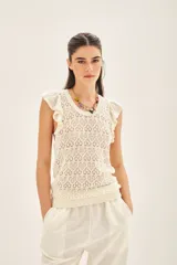 Musculosa tejida en hilo de algodón con punto desagujado, de calce al cuerpo y volados en las sisas.