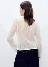 Jersey de punto calado color crudo, con cuello barco y mangas largas con puños acampanados.