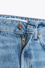 Pantalón de jean celeste de tiro alto, corte recto, con cinco bolsillos y cinturón marrón de cuero.