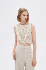 Top cropped color crudo, calado, al cuerpo y cuello a la base, sin mangas y con volados en los hombros.