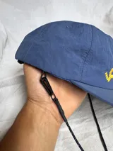 Gorra de béisbol azul marino con visera curva y bordado frontal en amarillo que dice "LOVE & PEACE" y debajo "PP:ONE".