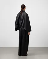 Pantalón negro de piel ovina, tiro alto con cintura cruzada y pinzas delanteras. Presenta volumen en la parte delantera izquierda y pierna ancha con corte horizontal a la altura de la rodilla.