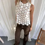 Top blanco sin mangas con cuello redondo y diseño calado con círculos.