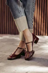 Zapatos de charol negro con diseño tipo T-bar, taco bajo cuadrado y punta redondeada.