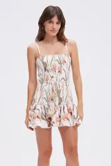 Vestido corto blanco con estampado floral en tonos naranja y verde, breteles finos, corte ajustado con falda con volados y lazo de cuerda en la cintura.