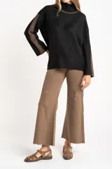 Sweater negro de tejido grueso con cuello alto acanalado. Presenta una franja decorativa en las mangas y el cuello en hilo marrón con brillo (lurex).