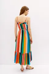Vestido midi estampado con rayas verticales multicolor, tirantes finos ajustables y detalle de lazo en el escote. Presenta un corte holgado con un volante fruncido en el ruedo.