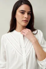 Camisa blanca de algodón con cuello mao, mangas abullonadas con puños abotonados y calados centrales.