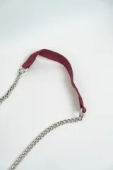 Cartera bandolera azul con tachas plateadas en forma de estrella, correa de cadena plateada y asa corta de cuero.