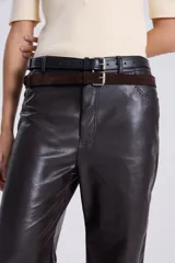 Pantalón recto de cuero sintético negro, estilo jeanero con tiro bajo, bolsillos delanteros y traseros, pretina con botón y pasacintos.