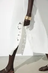Vestido largo blanco de tirantes finos ajustables con lazadas, escote redondo y detalle de aplicación de crochet a tono.