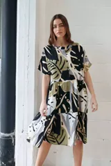 Vestido camisero midi con estampado de hojas en tonos negro, verde, gris y beige. Tiene cuello camisero, mangas cortas y cierre frontal con botones.
