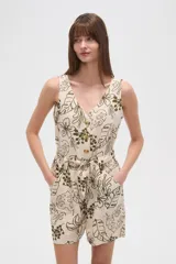 Mono corto sin mangas, entallado, con cuello en V y cierre frontal de botones. El tejido es de lino y viscosa con estampado tropical en tonos verde oliva sobre fondo beige claro. Incluye cinturón de lazo a juego.