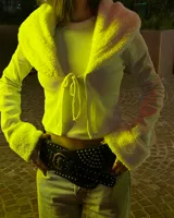 Cardigan corto blanco con cuello de piel sintética y cierre frontal con lazos. Mangas largas acampanadas y tejido de punto acanalado.