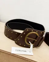 Cinturón marrón ancho de ecocuero con hebilla circular dorada y tachas pequeñas doradas.