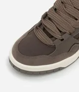 Championes de estilo urbano, color beige claro, con cordones gruesos trenzados y suela ancha de plataforma en tonos crema y gris. Presenta recortes en material sintético liso y gamuzado.