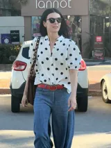 Camisa blanca de muselina con estampado de lunares negros, manga corta abullonada y botones al frente.