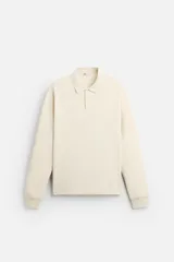 Polo color crema de manga larga con cuello solapa y cierre frontal de botonadura.