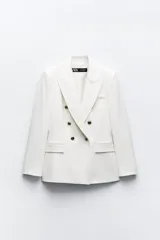 Blazer color blanco hueso, de corte entallado y doble botonadura dorada. Tiene cuello con solapa, mangas largas con hombreras y bolsillos delanteros con solapa.