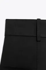Shorts de tiro alto color negro, con trabillas en la cintura, bolsillos laterales y cierre frontal con cremallera y ganchos metálicos.