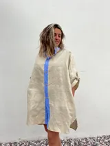 Vestido camisero beige de lino con cuello y solapa azul lavanda, cierre frontal con botones y mangas largas.