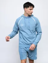 Canguro de felpa color crema con capucha, cordones y logo Umbro bordado en rojo. Presenta ribete rojo en hombros y bolsillo tipo canguro con cierre lateral.