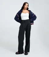 Pantalón de vestir de corte recto, color gris oscuro con finas rayas verticales (raya de tiza). Presenta pliegues frontales y tiro alto.