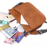 Cartera de eco cuero color marrón con correas decorativas y cierre superior.