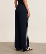 Pantalón deportivo azul marino de corte ancho, con cintura elástica, bolsillos laterales y dos rayas verticales blancas a lo largo de cada pierna.