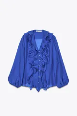 Camisa azul con escote en pico, cierre frontal con botones, mangas largas abullonadas con elástico en los puños y detalle de volantes en el frente.