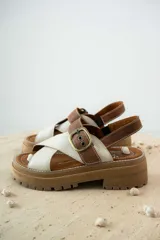 Sandalias bajas color marrón de cuero gamuzado, con tiras cruzadas y hebilla metálica.