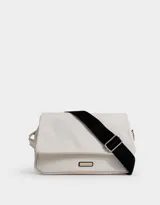 Bandolera color blanco con correa regulable negra, solapa con broche imantado y tag de goma con logo.