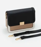 Cartera mediana de PU color negro, con asa transversal regulable, detalle metálico dorado en el frente y recortes contrastantes en beige y blanco.
